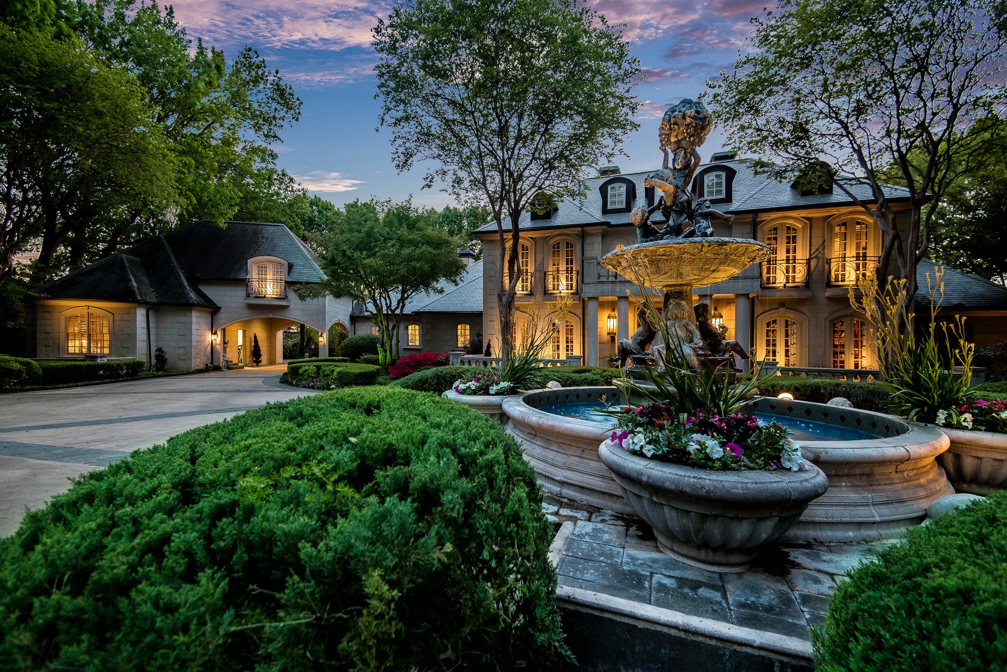 Twilight exterior of a luxury home with a fountain
