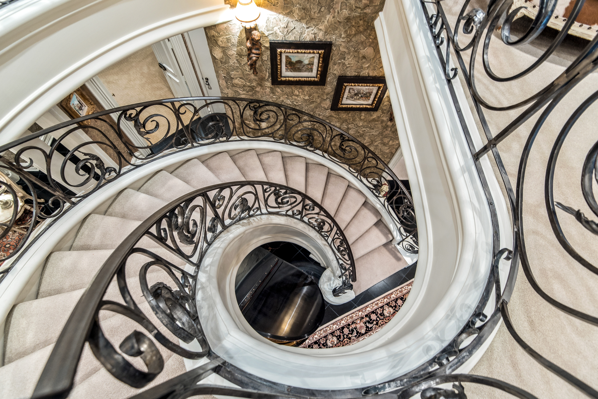 Looking down a spiral staircase with an iron railing