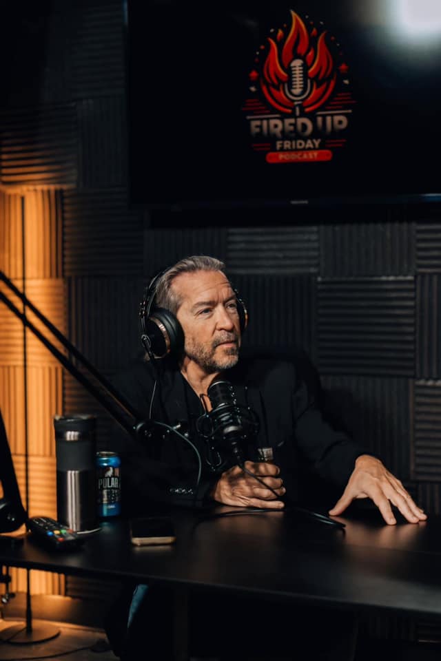 Podcast guest speaking into a microphone on a dark studio set