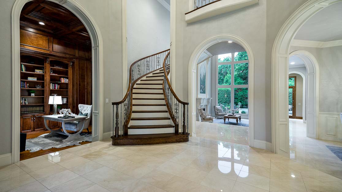 Entry with a curved staircase and wood-paneled study