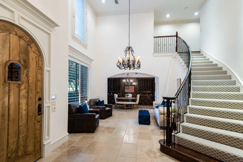 Two-story living room with a curved staircase and chandelier